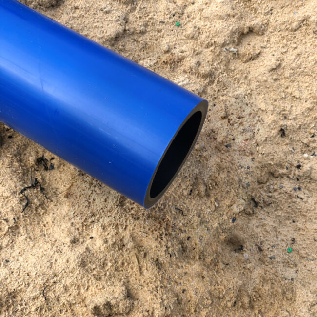 Hier ist das blaue Rohr auf sandigem Untergrund ohne einer Baustellenkappe zu sehen. Die Monteure können das Rohr ungehindert weiter bearbeiten.